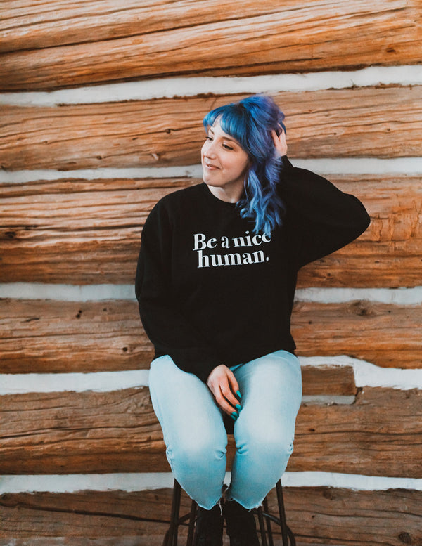 woman with blue hair sitting on chair wearing sweater 